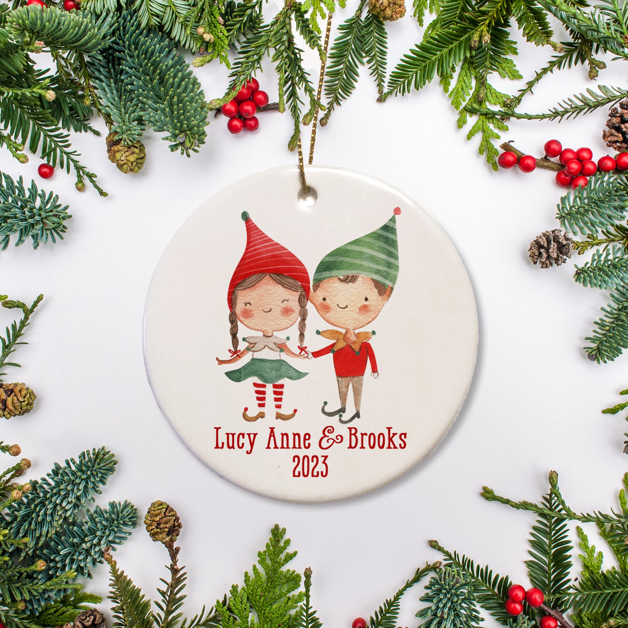 A sweet boy and girl elf picture on a ceramic ornament with the name and the date.