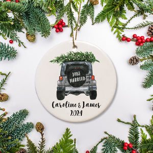 A keepsake ornament of a jeep which says “Just Married” with a Christmas tree which is personalized and includes the year. The jeep is gray..
