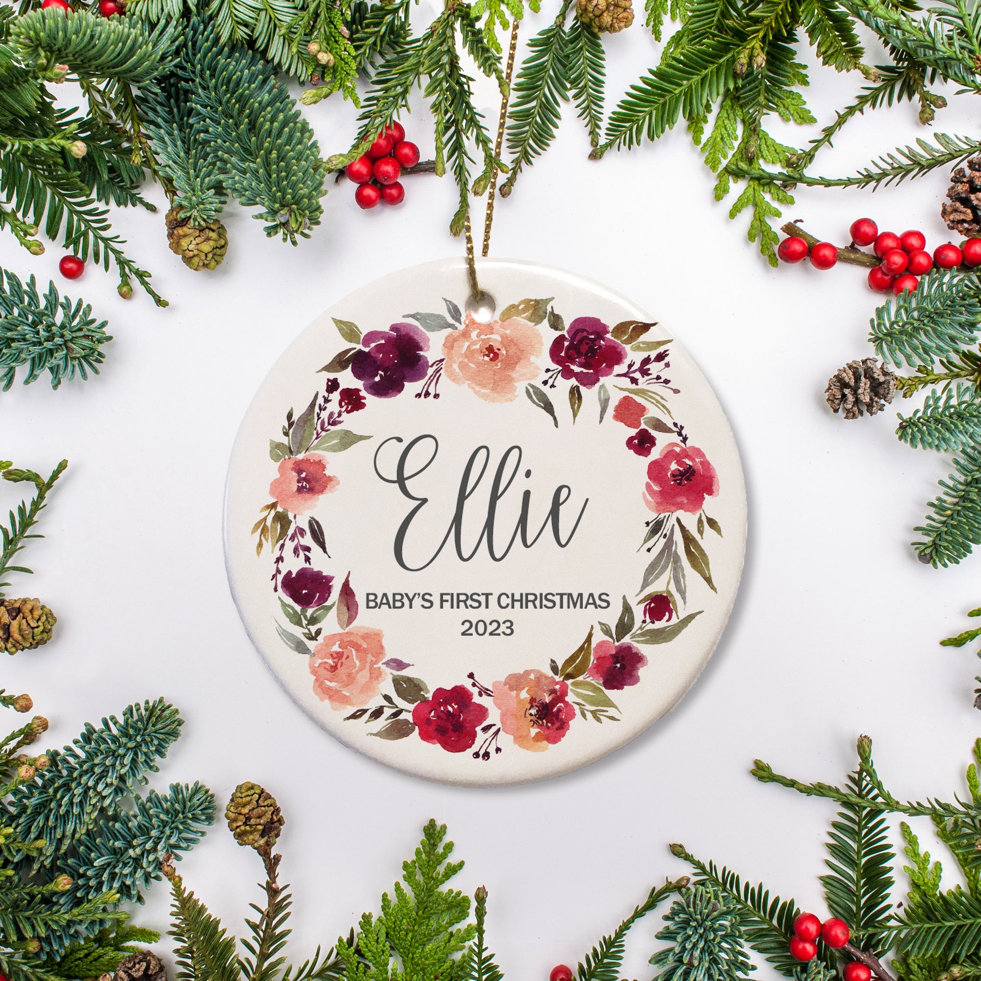 A watercolor wreath of coral and burgundy roses surround the name and year.  It shows that it is the First christmas.