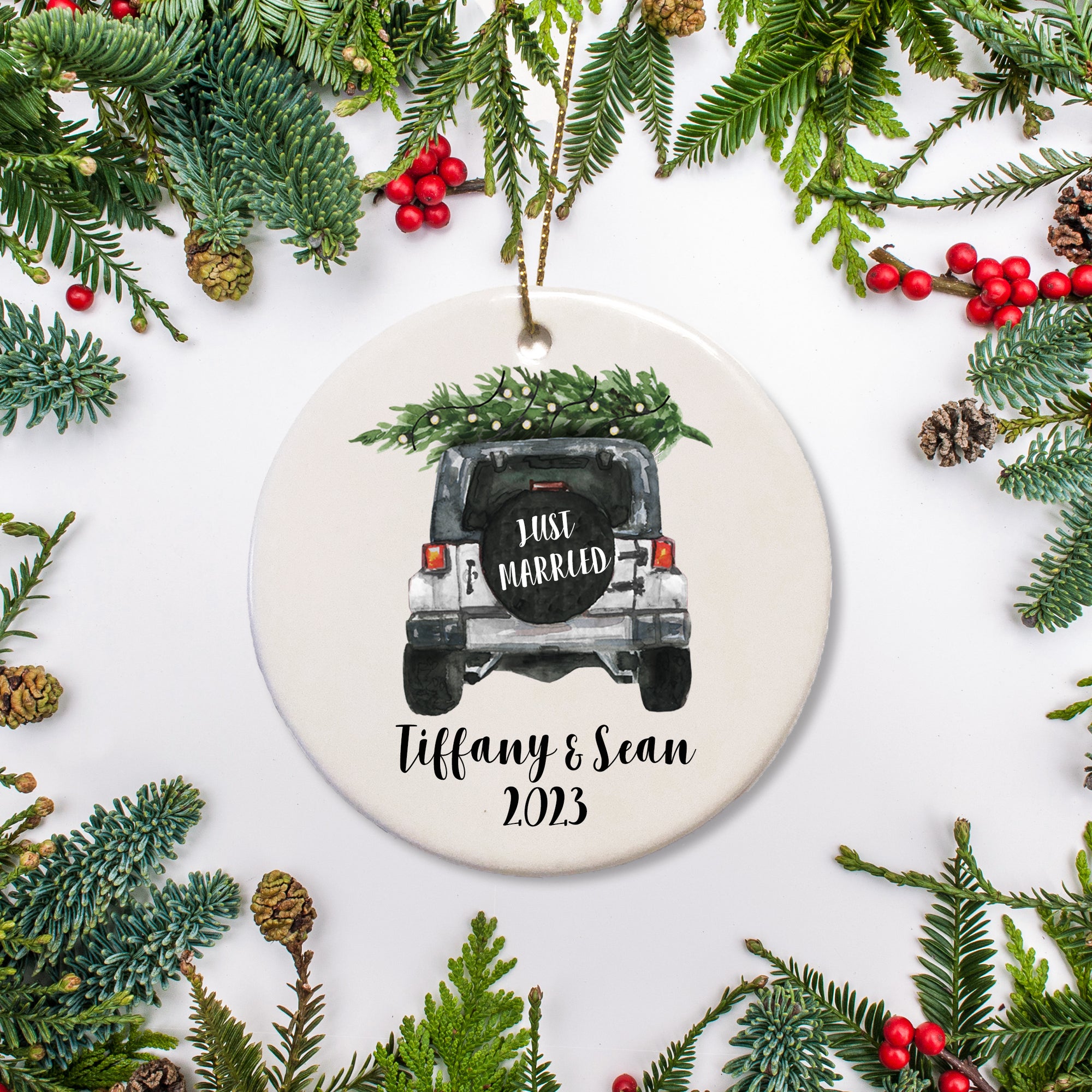 A keepsake ornament of a jeep which says “Just Married” with a Christmas tree which is personalized and includes the year. The jeep is white.