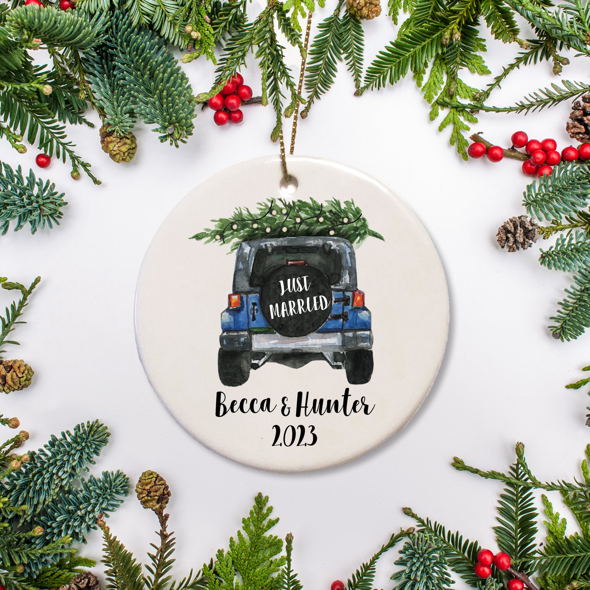 A keepsake ornament of a jeep which says “Just Married” with a Christmas tree which is personalized and includes the year. The jeep is blue.
