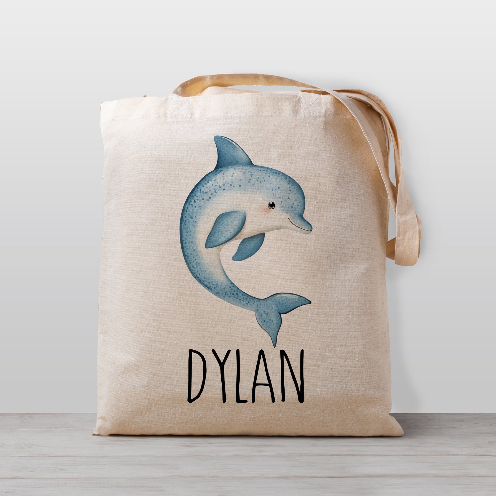 Tote bag with a dolphin design and the your child's name on a light weight beige tote bag