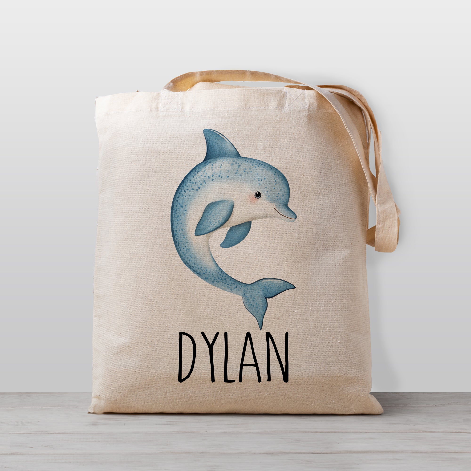 Tote bag with a dolphin design and the your child's name on a light weight beige tote bag