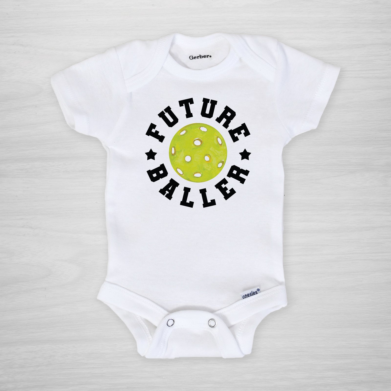 Future Baller Pickleball Gerber Onesie®. You can leave a note and specify team colors for the text. Otherwise, the print will be black as shown. Makes a great baby shower gift for your favorite picklehead.