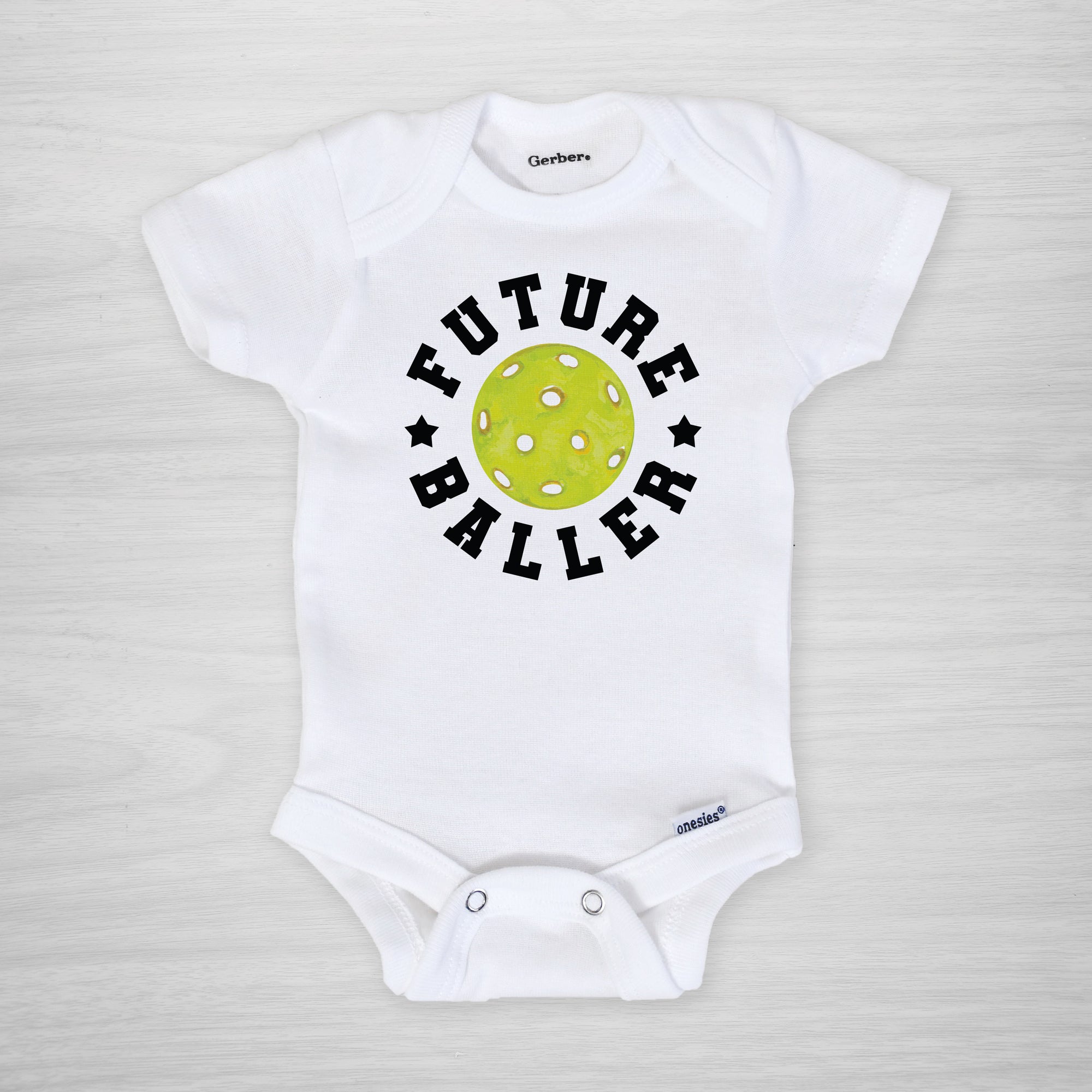 Future Baller Pickleball Gerber Onesie®. You can leave a note and specify team colors for the text. Otherwise, the print will be black as shown. Makes a great baby shower gift for your favorite picklehead.