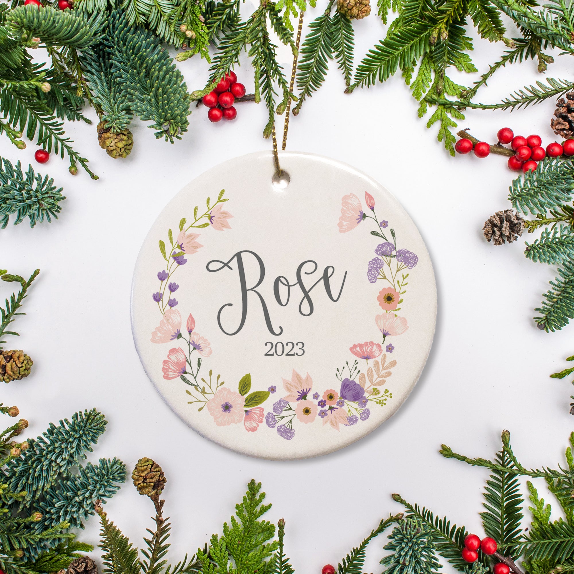 A wreath of pink and purple blossoms surround the name and year of this keepsake ornament.