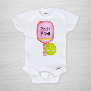 Pickleball Gerber Onesie® with a pink paddle. You can leave a note and specify team colors for the text. Otherwise, the print will be black as shown. Makes a great shower gift for the new pickle baby