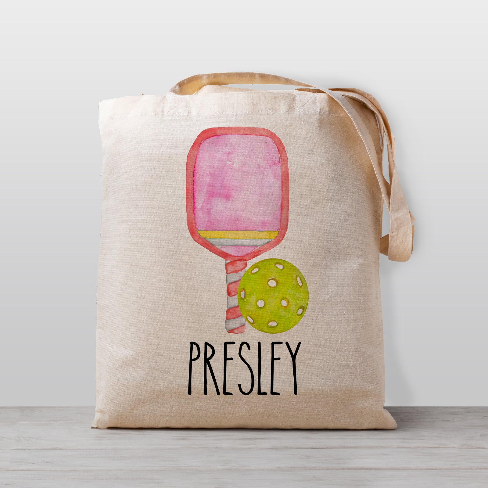 A pickleball personalized tote bag, featuring a pink paddle and a pickleball. Perfect for carrying your little one's stuff to preschool, kindergarten, or as a library book bag.