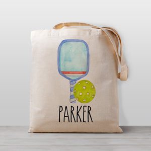 A pickleball personalized tote bag, featuring a blue paddle and a pickleball. Perfect for carrying your little one's stuff to preschool, kindergarten, or as a library book bag.