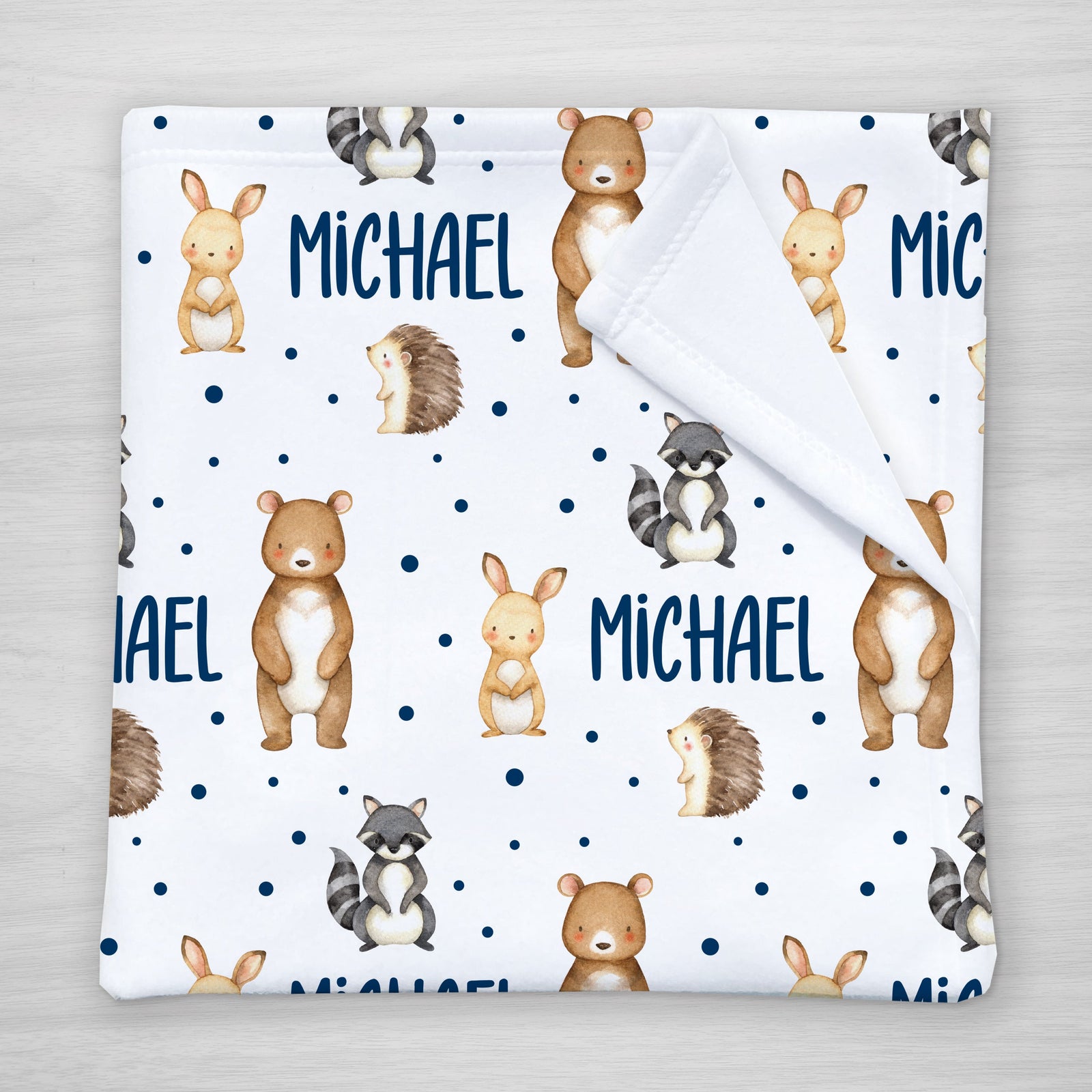 Blanket with forest animal pattern and personalized with your child's name. Features a bear, bunny, raccoon, and hedgehog