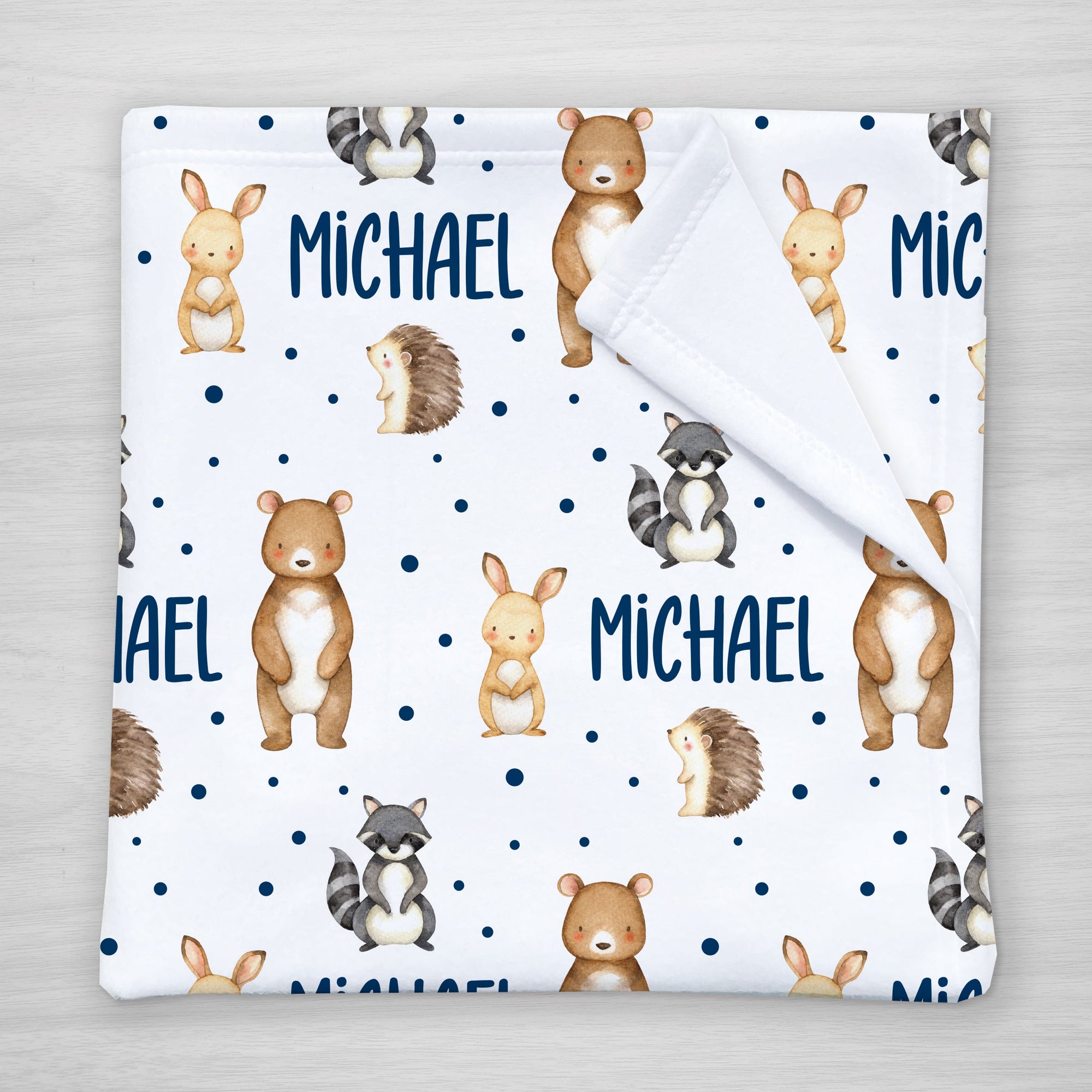 Blanket with forest animal pattern and personalized with your child's name. Features a bear, bunny, raccoon, and hedgehog