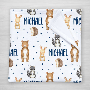 Blanket with forest animal pattern and personalized with your child's name. Features a bear, bunny, raccoon, and hedgehog