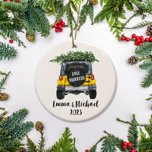 A keepsake ornament of a jeep which says “Just Married” with a Christmas tree which is personalized and includes the year. The jeep is yellow.