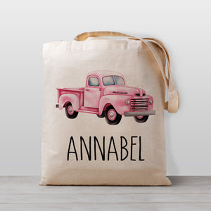 A pink pickup truck on a personalized tote bag, perfect for carrying your little one's stuff to kindergarten, or bringing favorite books over to Grandma's house.
