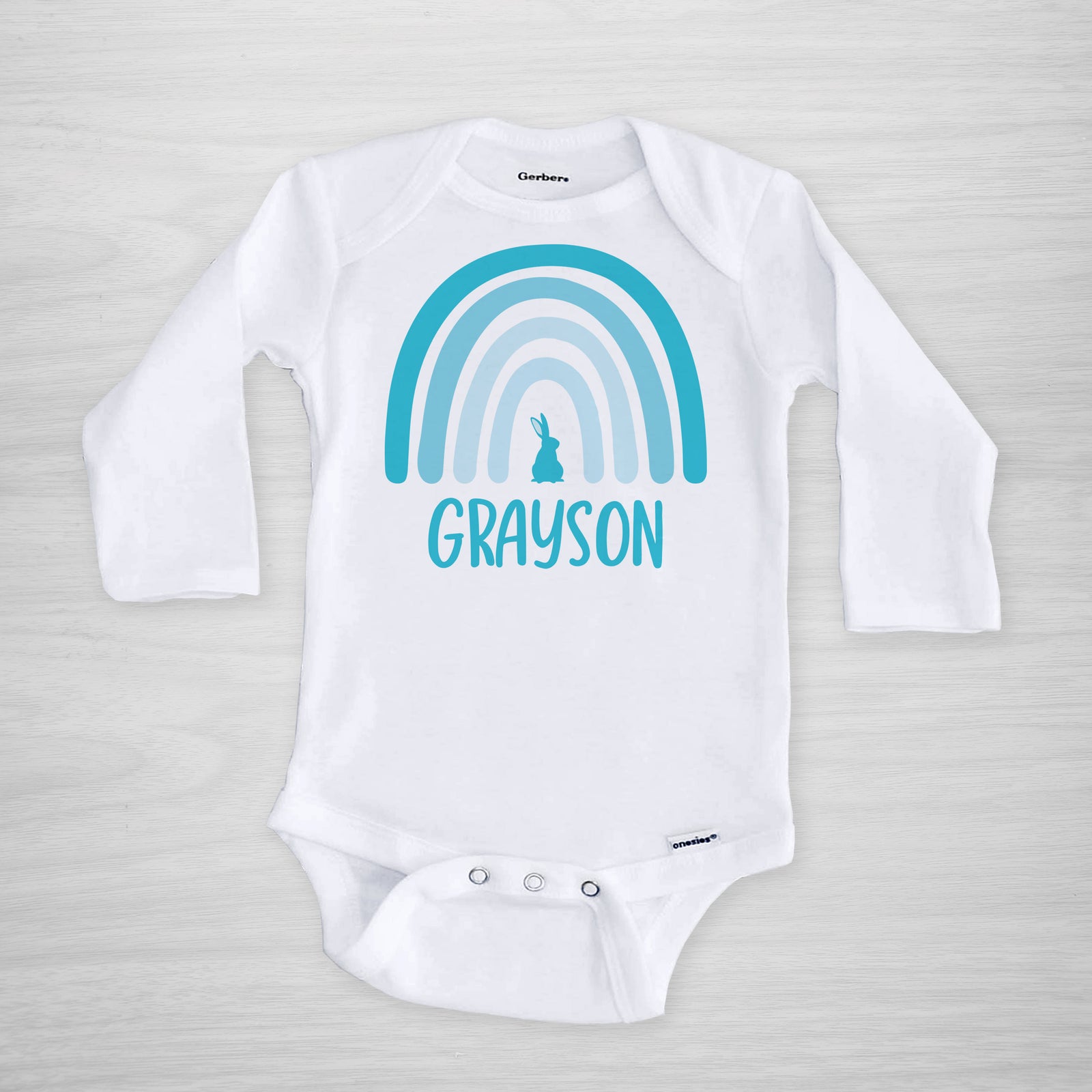 This Easter onesie features your little one's name and a modern blue boho Easter rainbow with a bunny.