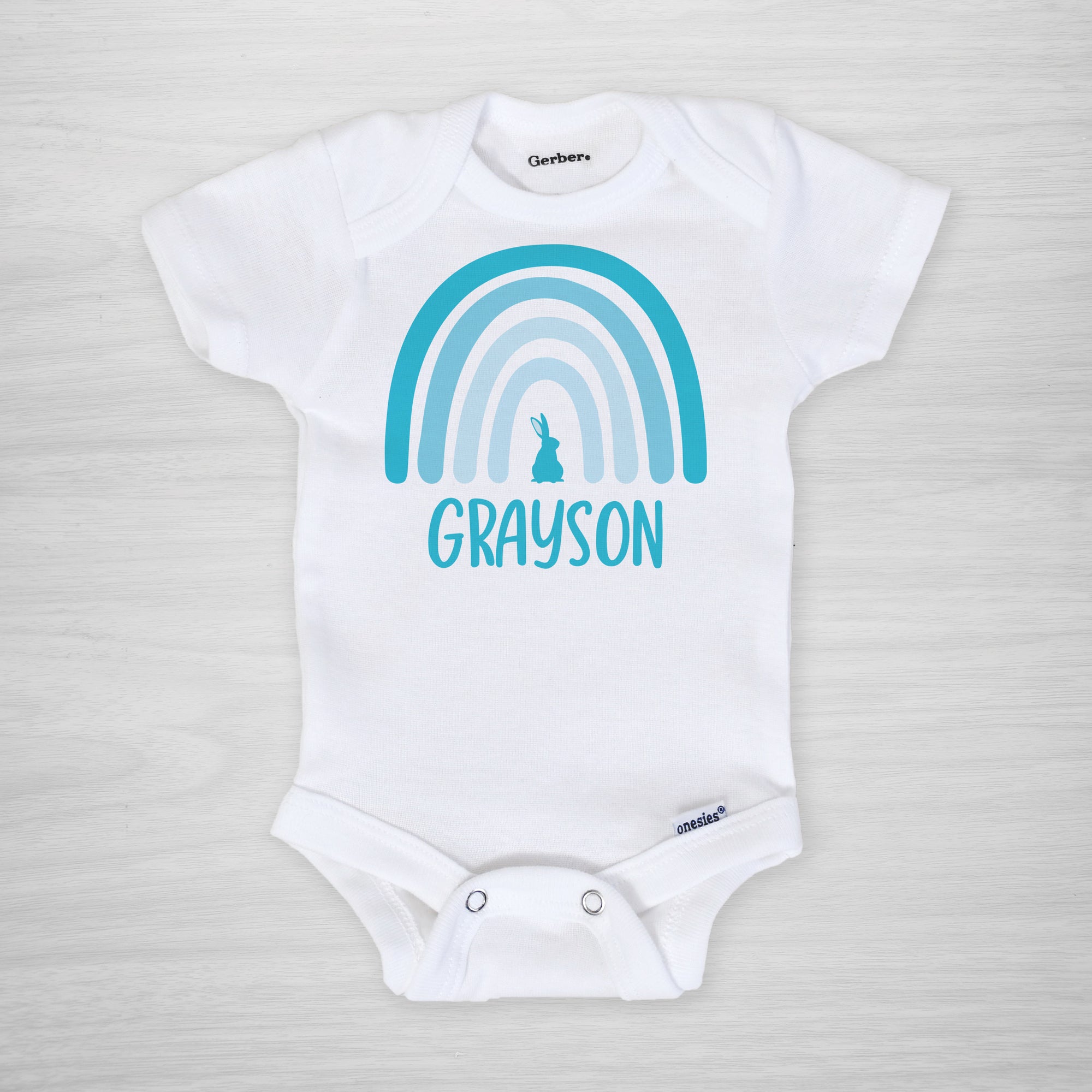 This Easter onesie features your little one's name and a modern blue boho Easter rainbow with a bunny.