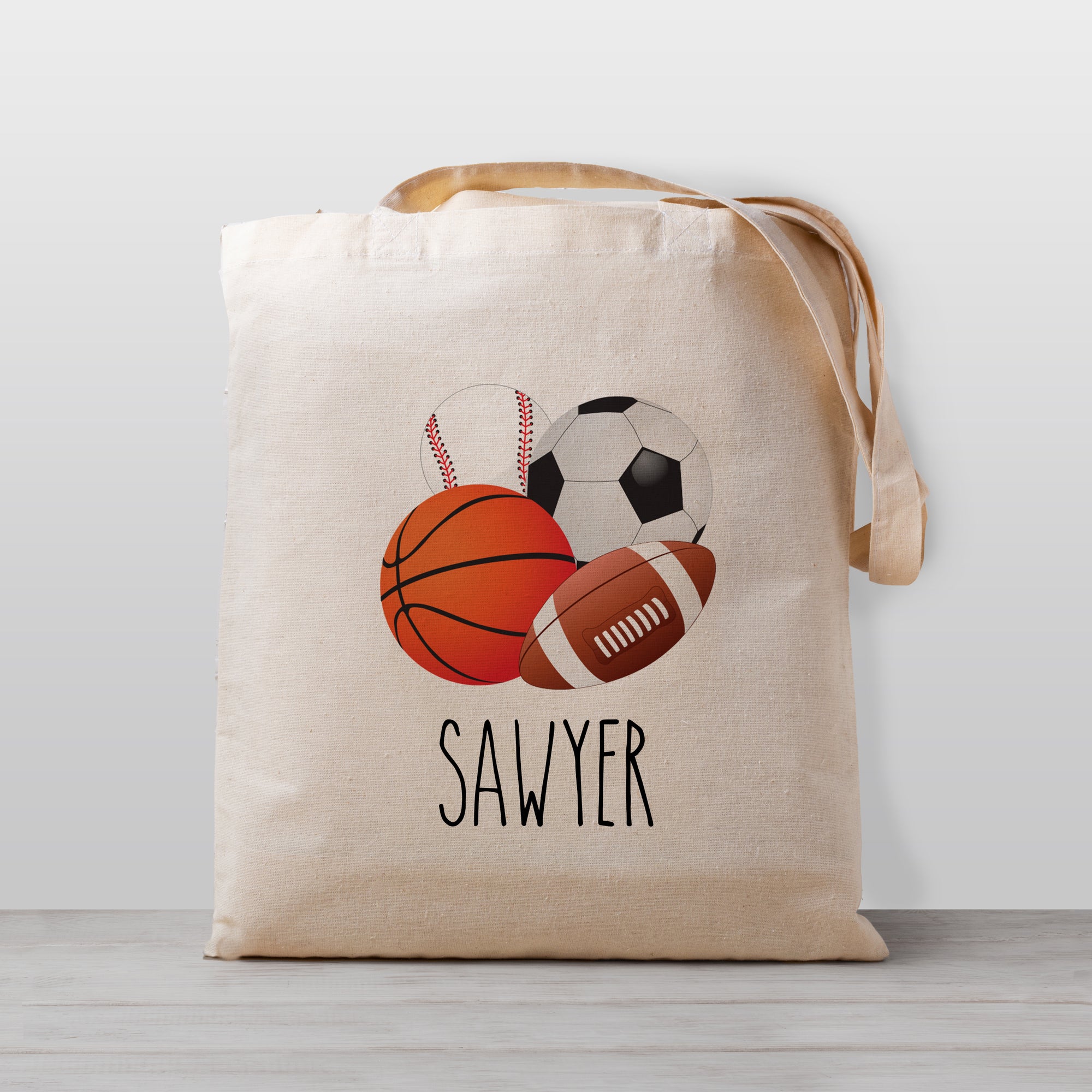 A sports personalized tote bag, featuring a basketball, soccer ball, football, and baseball. 
