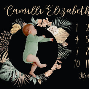Bold Tropical Floral milestone blanket, black background with beige text, posed with baby