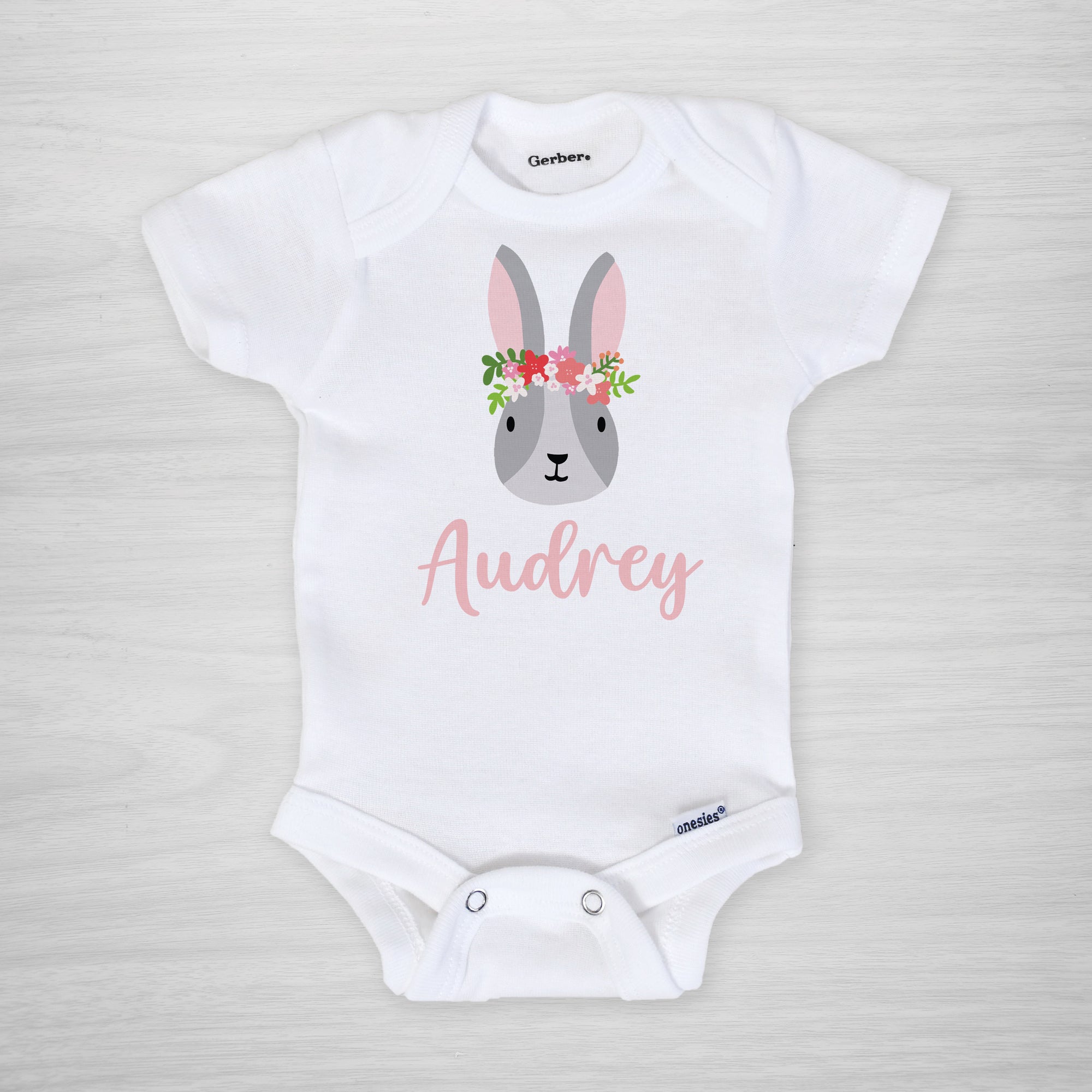 This onesie features a sweet Easter bunny with a crown of flowers, and your little one's name, short sleeved
